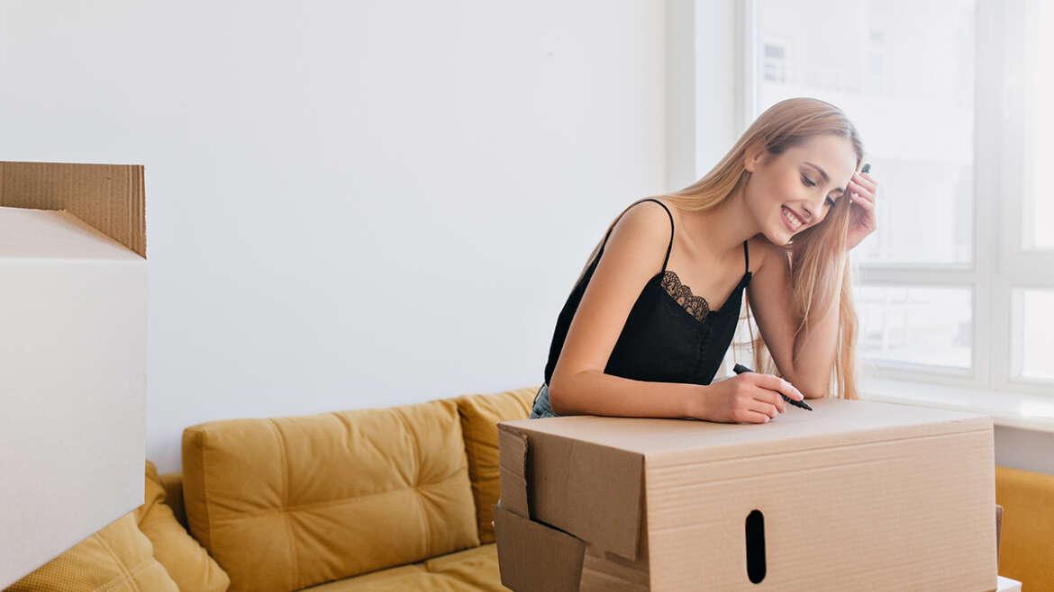 Young woman packing a box for moving, TrekMovers