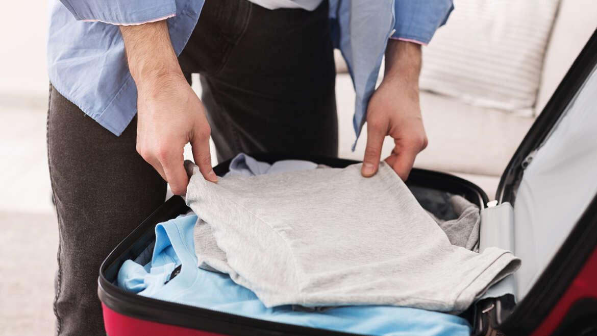 Person packing clothes into a suitcase for moving, TrekMovers