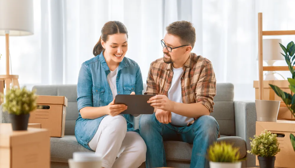 Couple looking at a tablet while planning their move online, TrekMovers