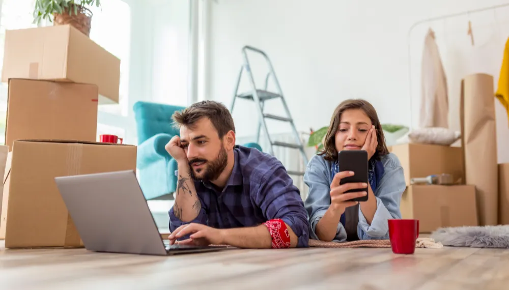 Couple checking moving quotes on their devices, TrekMovers