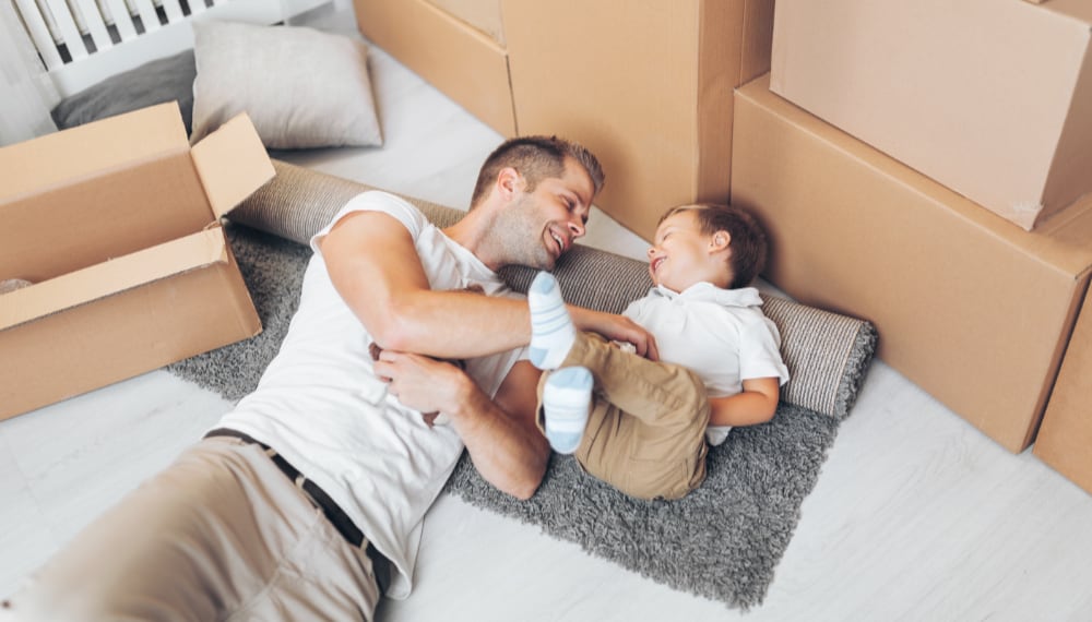 Man lying on the floor with a child near moving boxes, TrekMovers
