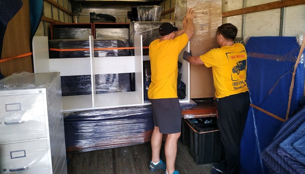 Men loading a moving truck with furniture and boxes, TrekMovers