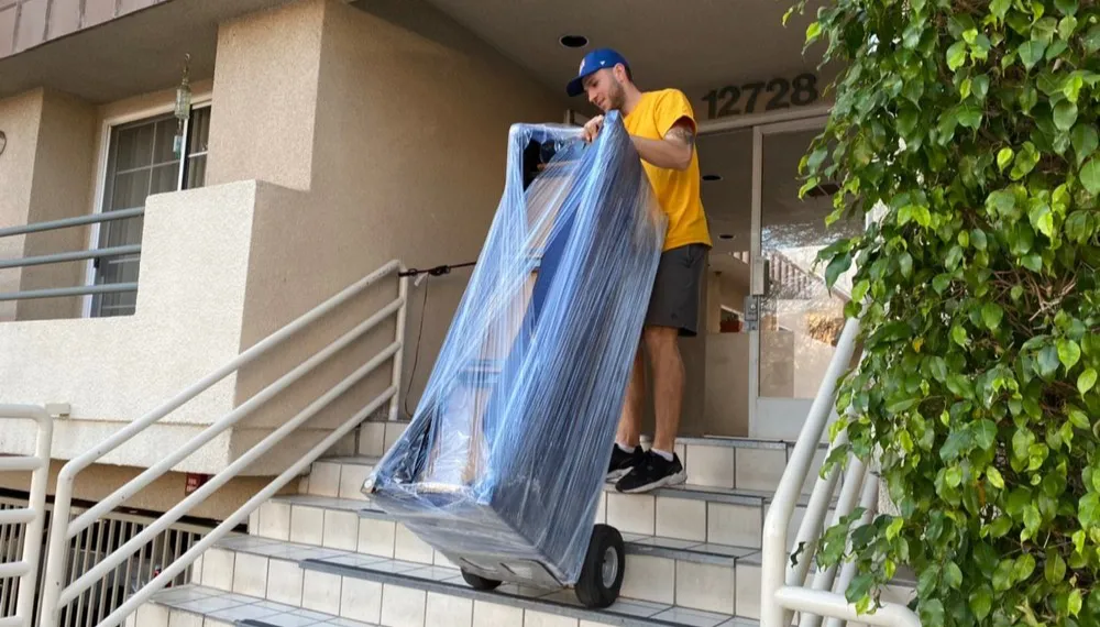 Man carefully moving packed furniture down the stairs, TrekMovers