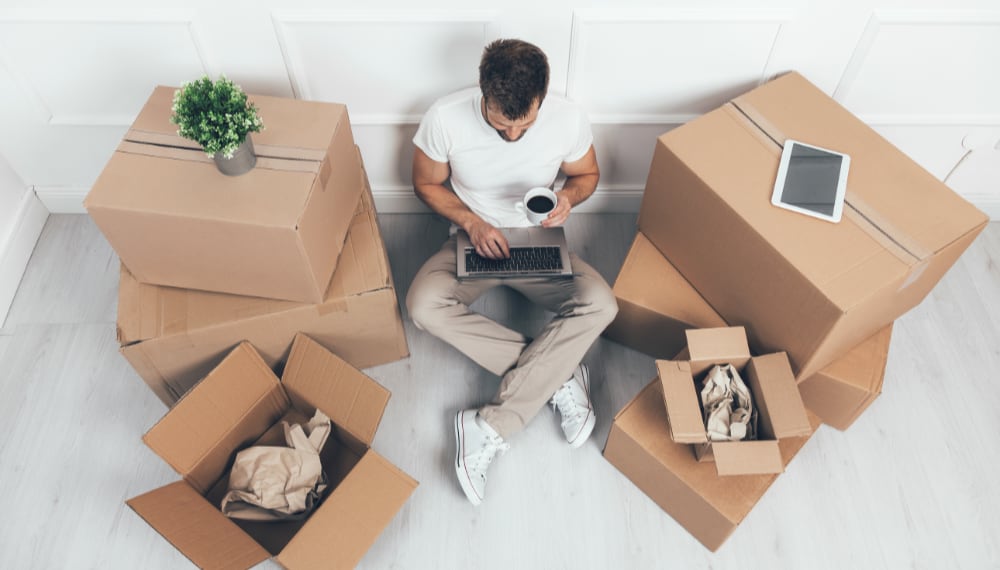 Man drinking coffee among moving boxes during a break, TrekMovers